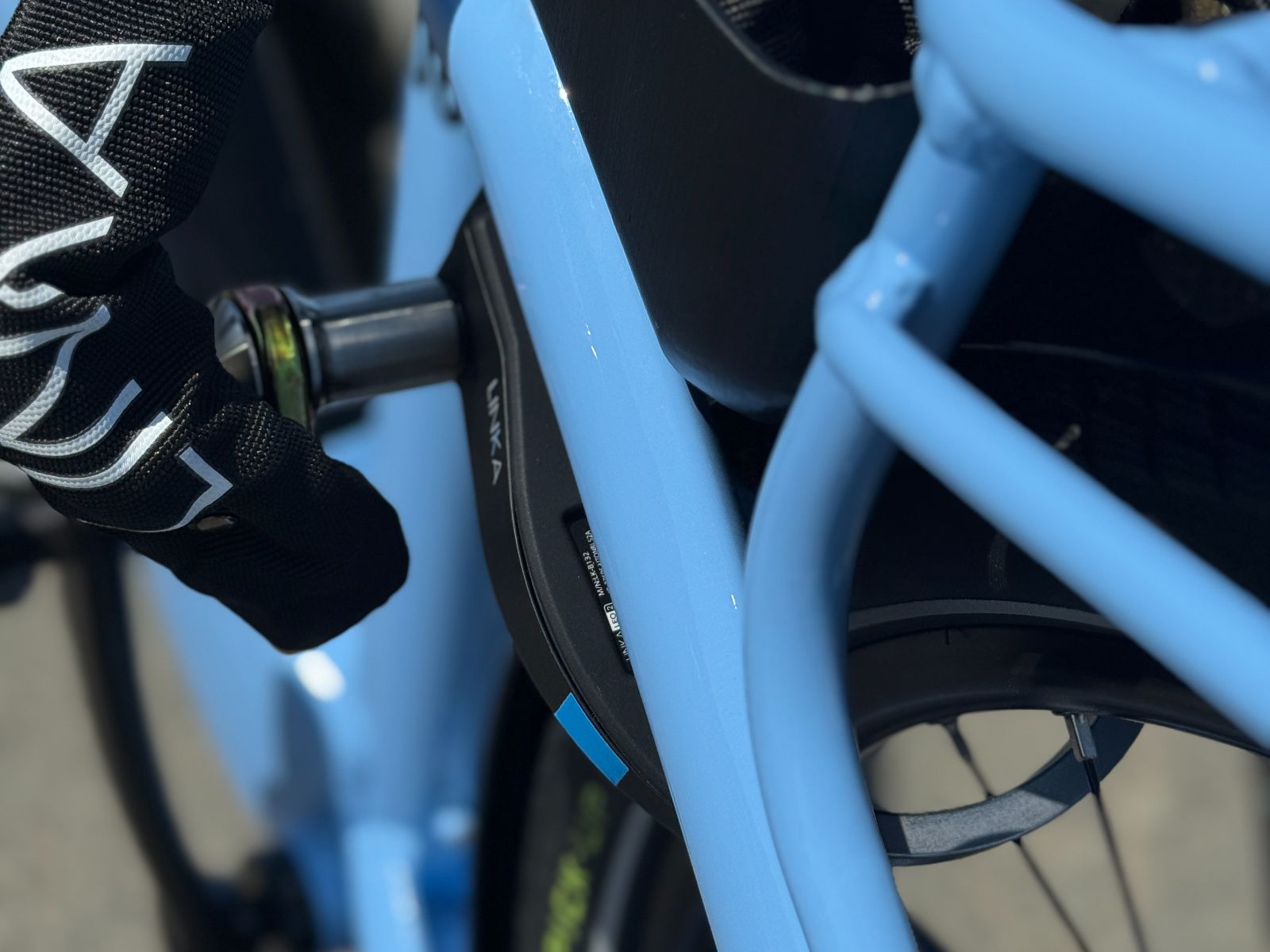 Close-up of a LEO 2 Pro lock with TetherSense chain plugged in on a blue e-bike