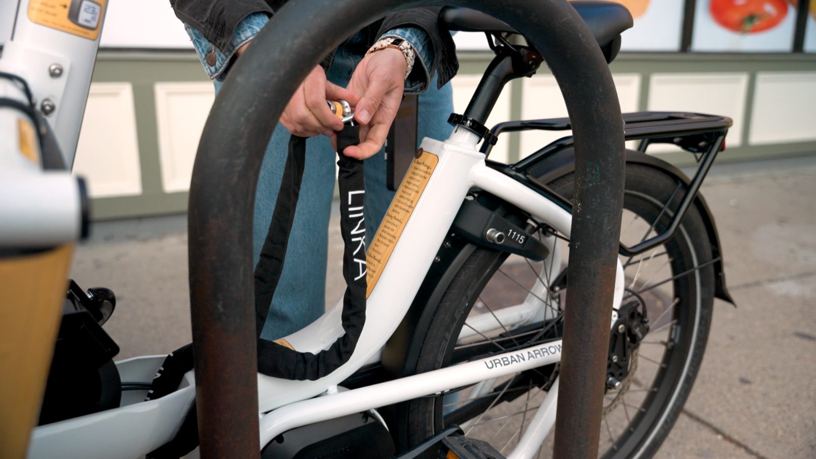 Rider threading a TetherSense chain through a bike rack